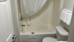 A bathroom with a bathtub, toilet, and a towel rack. - Stay Lodge Decatur (Decatur)