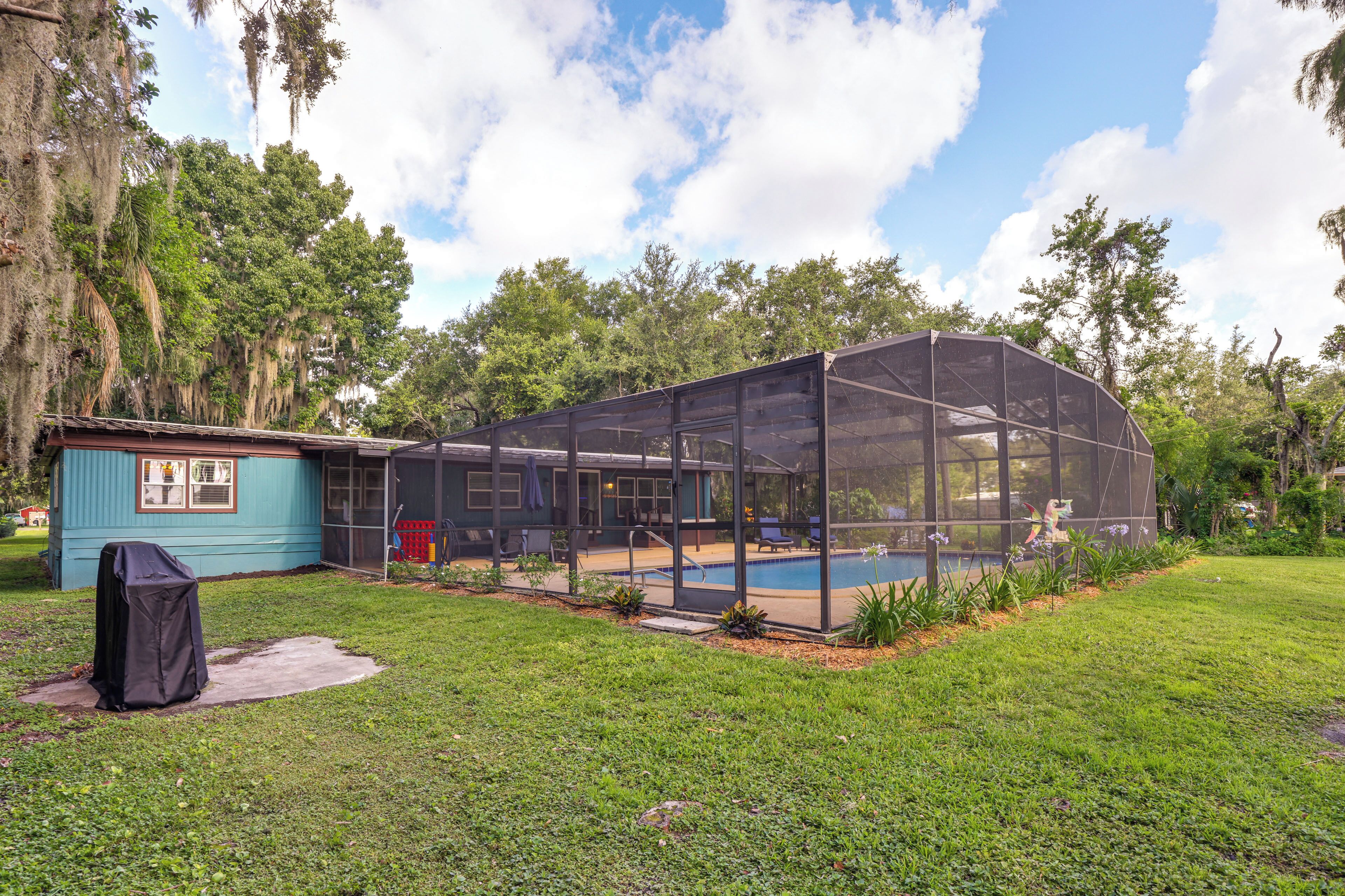 A house with a covered outdoor area, a swimming pool, and a blue building.
