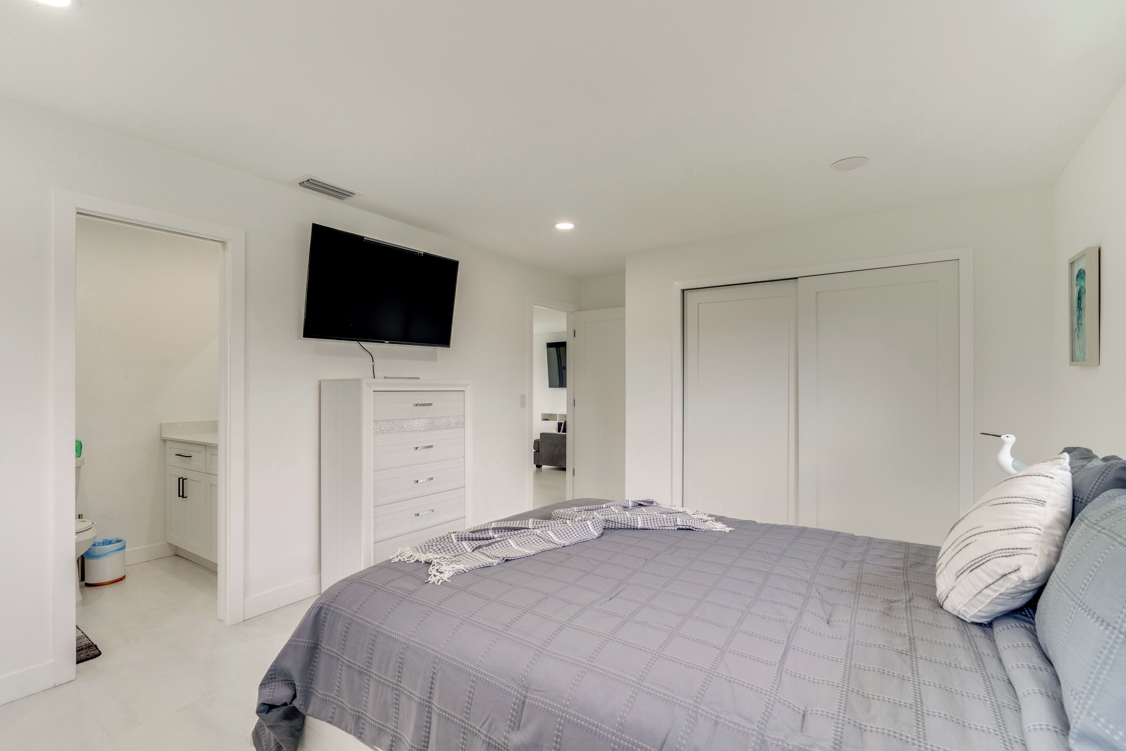 Un dormitorio con cama, televisor, armario y puerta.