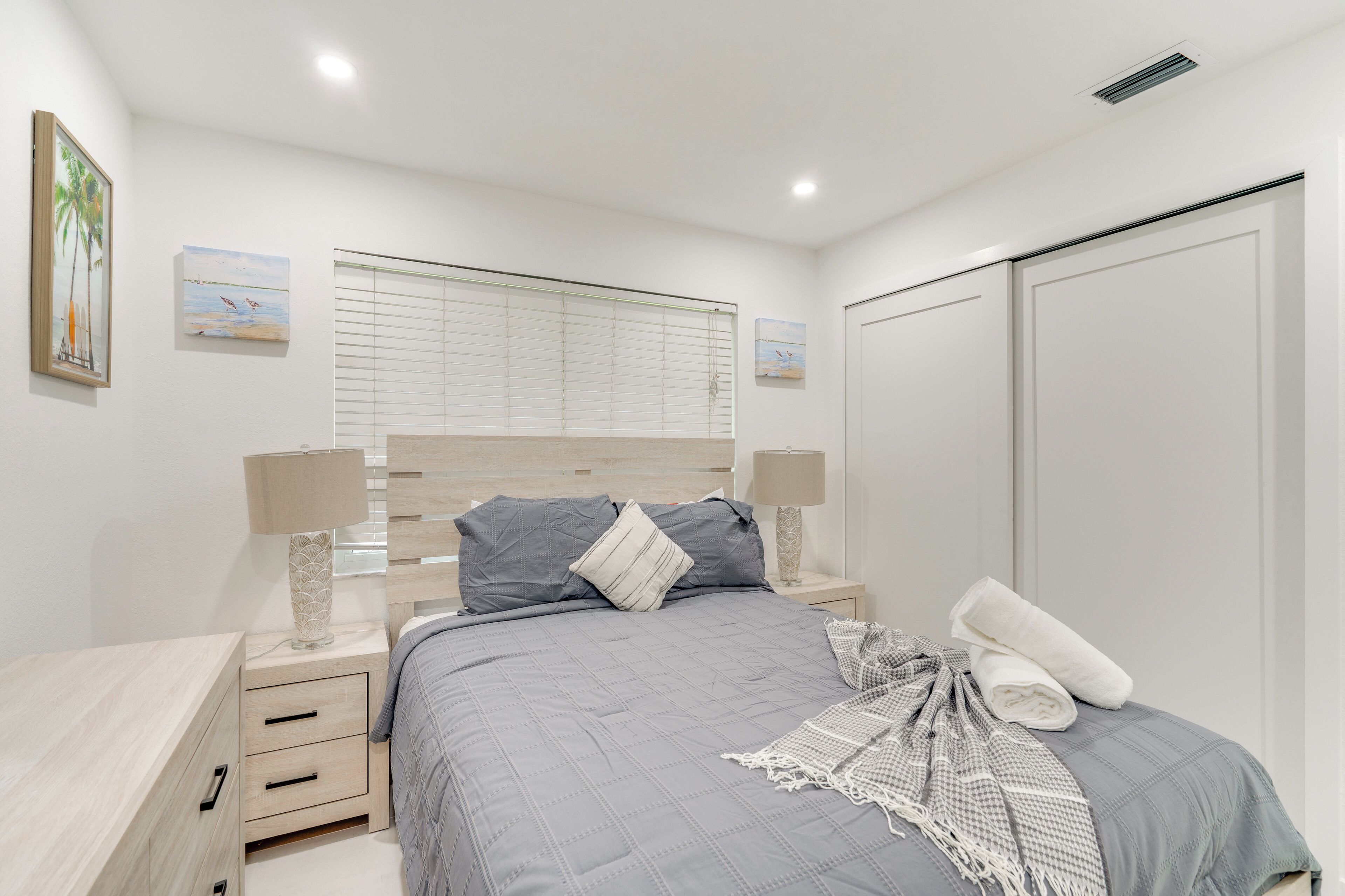 A bedroom with a bed, nightstands, a wardrobe, and artwork on the walls.