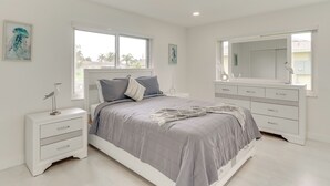 A bedroom with a bed, nightstands, a dresser, and a large mirror. - Swim, Golf & Explore: Pet-friendly Cape Coral Home (Cape Coral)