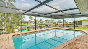 A swimming pool with a glass enclosure, surrounded by a brick patio. - Swim, Golf & Explore: Pet-friendly Cape Coral Home (Cape Coral)