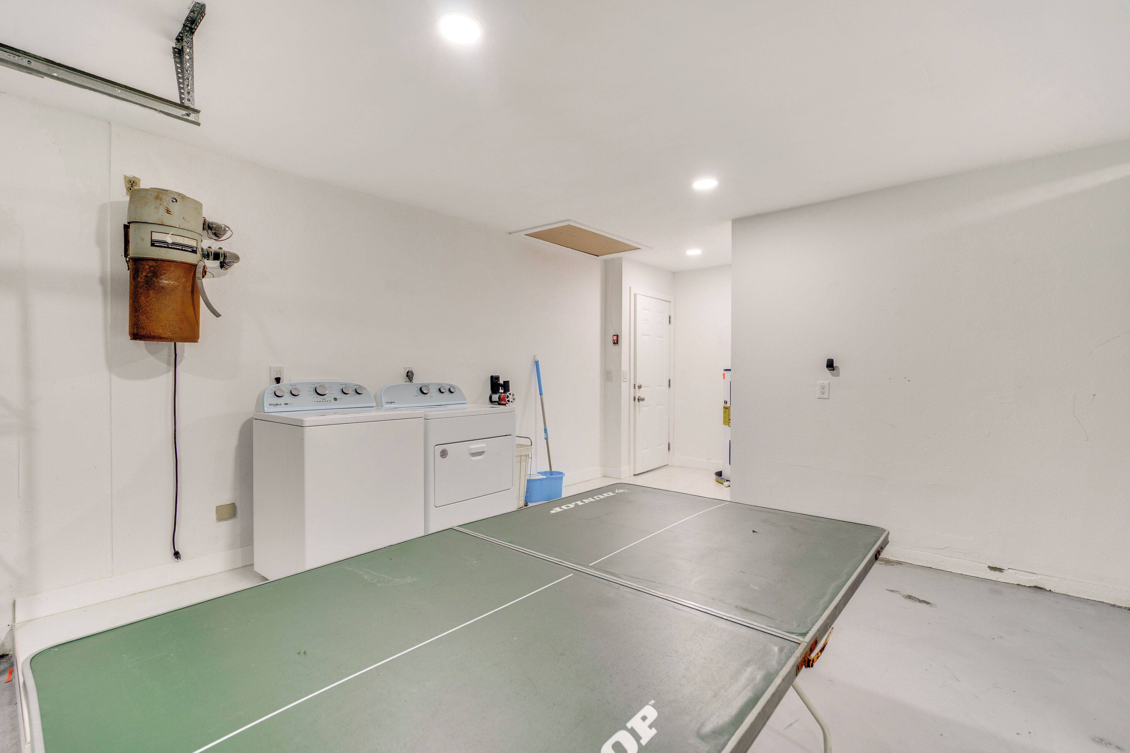 Ein Zimmer mit einem Tischtennisplatten, einer Waschmaschine und einem Mop.