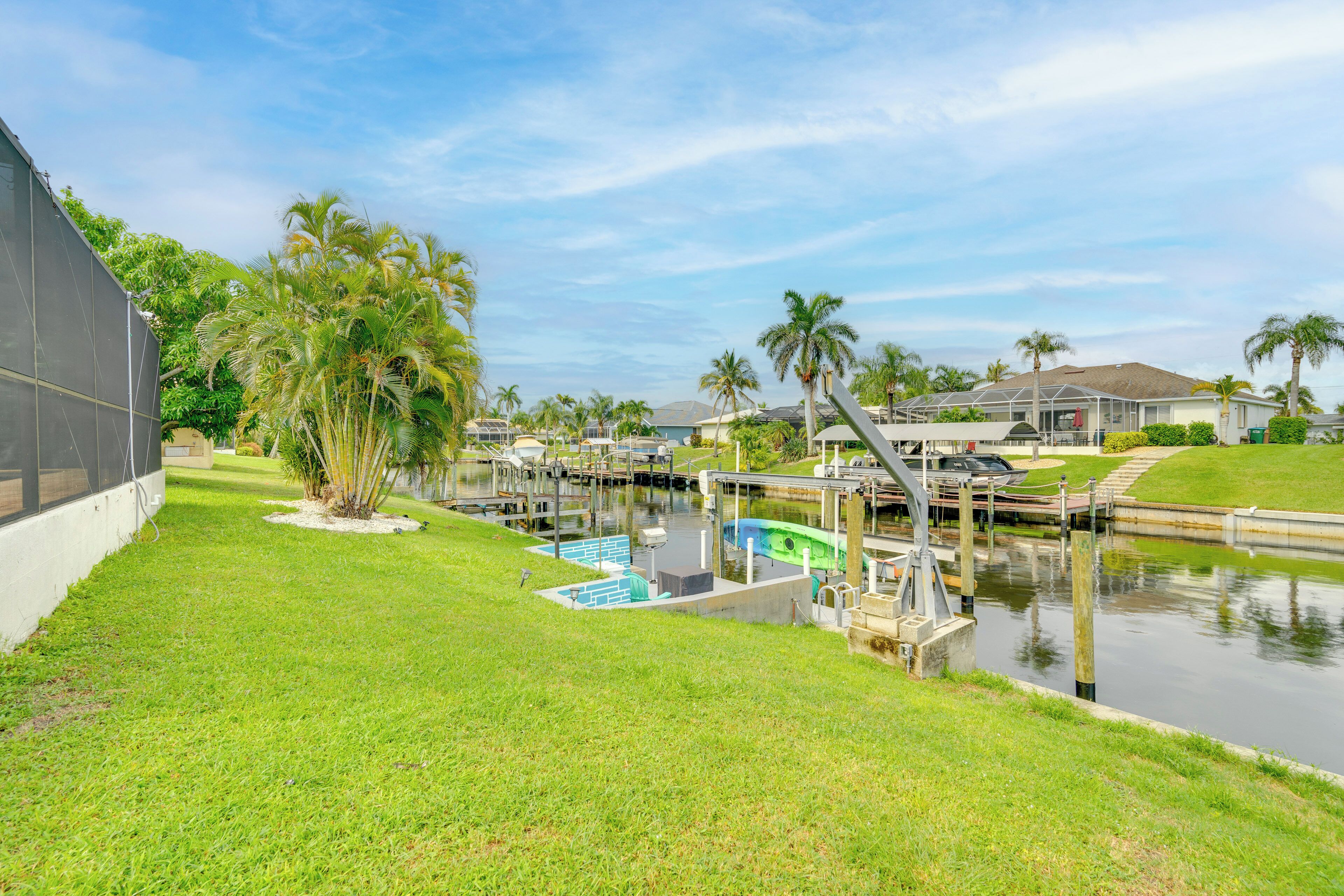 A marina with boats docked, a swimming pool, and a grassy area with palm trees.