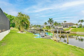 A marina with boats docked, a swimming pool, and a grassy area with palm trees. - Swim, Golf & Explore: Pet-friendly Cape Coral Home (Cape Coral)
