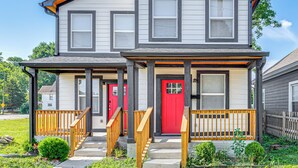 A two-story house with a red front door, a covered porch with wooden railings, and a small front yard. - Sip, Dine & Explore Fountain Square: Indy Retreat! (Indianapolis)