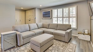 A living room with a sectional sofa, ottoman, and a small side table.