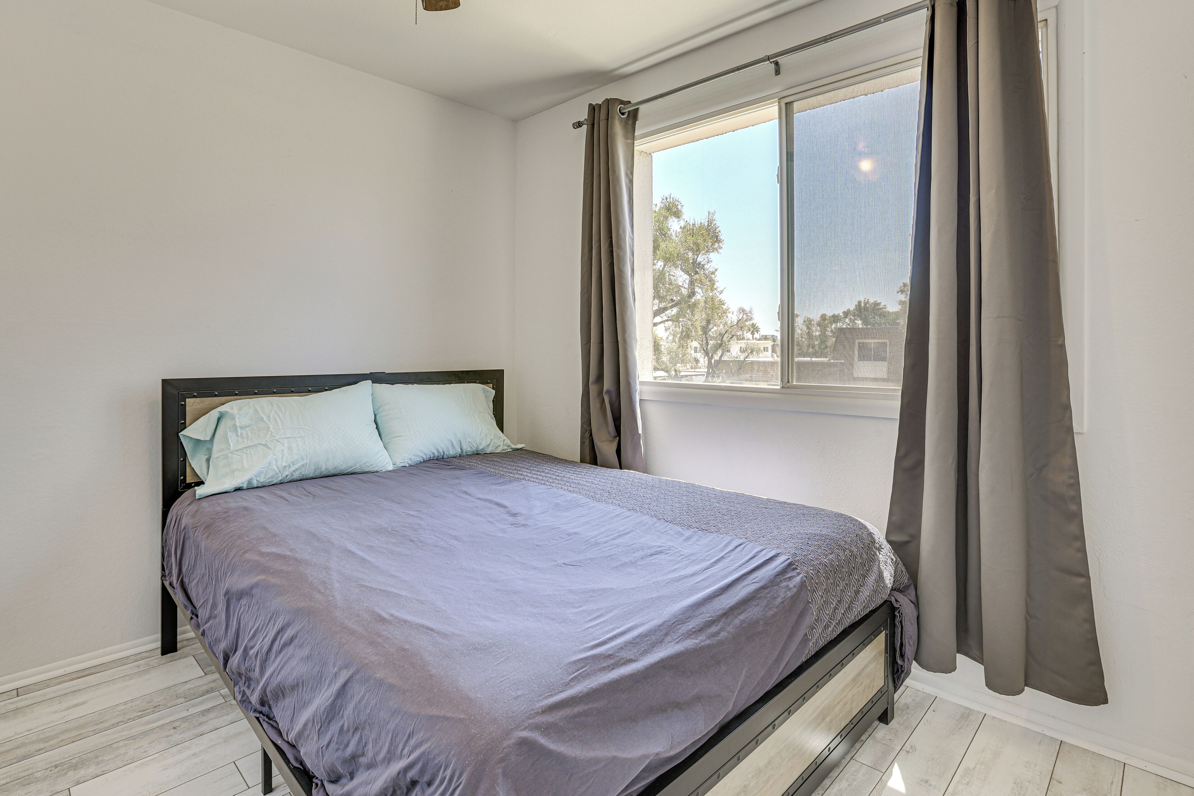 Un dormitorio con cama, ventana y cortinas.