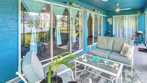 A room with a teal-colored wall, a glass partition, a sofa, a coffee table, and a ceiling fan. - Golf & Hike: Family Home in Rotonda West! (Rotonda West)