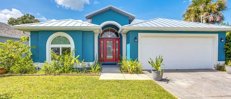 A two-story house with a red front door, a garage, and a well-maintained lawn.