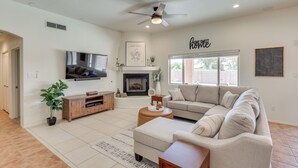 A spacious living room with a large sectional sofa, a flat-screen TV mounted on the wall, a fireplace, and a ceiling fan. - 1 Mi to Golf Course: Yuma Oasis w/ Furnished Patio (Yuma)