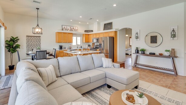 A modern living room with a sectional sofa, a dining area, and a kitchen with wooden cabinets and stainless steel appliances. - 1 Mi to Golf Course: Yuma Oasis w/ Furnished Patio (Yuma)