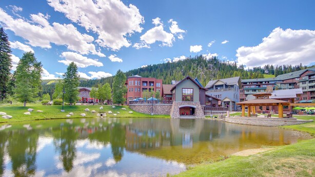 A lakeside hotel with a stone bridge, a pond, and mountain views. - 100 Steps to Gondola: Cozy Winter Park Condo! (Winter Park)