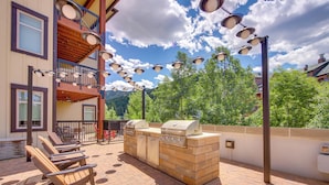 An outdoor patio with a barbecue grill, lounge chairs, and a balcony with a railing. - 100 Steps to Gondola: Cozy Winter Park Condo! (Winter Park)