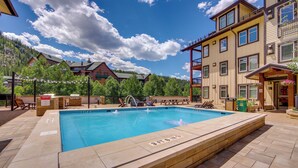 A rectangular pool with a 3ft 6in depth marker, surrounded by a patio with lounge chairs and a wooden deck. - 100 Steps to Gondola: Cozy Winter Park Condo! (Winter Park)