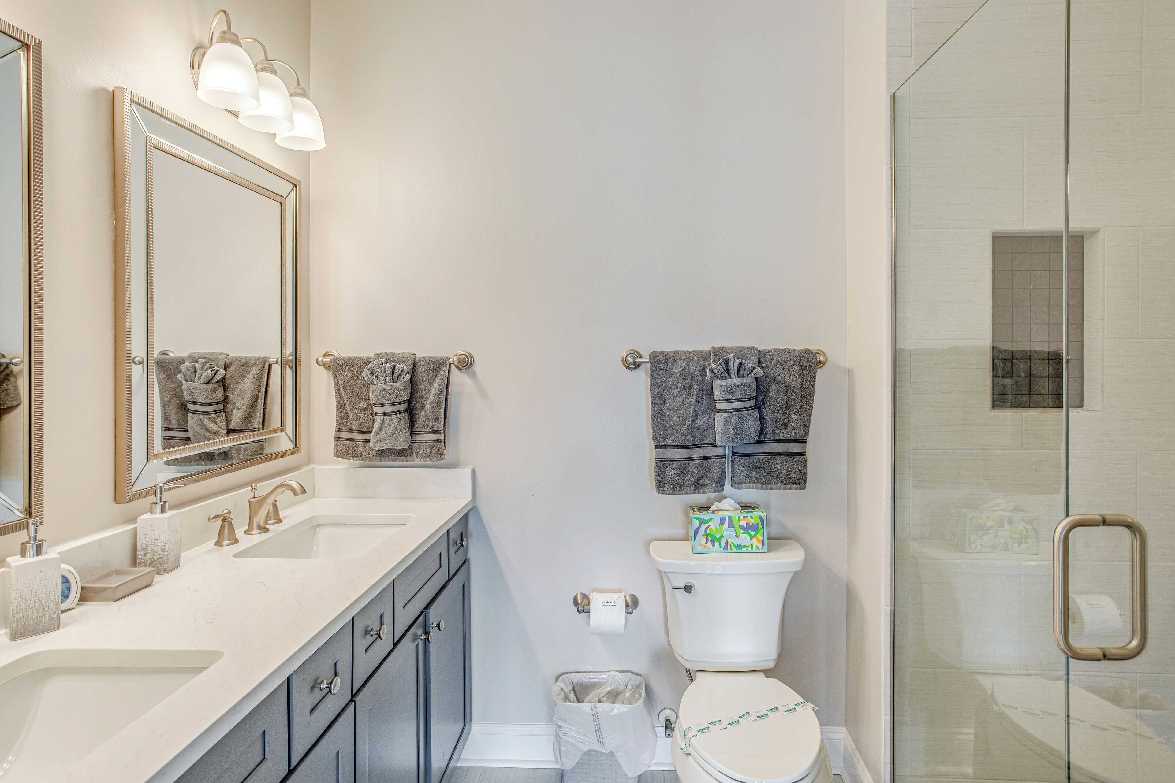 A bathroom with a sink, mirror, toilet, and shower.