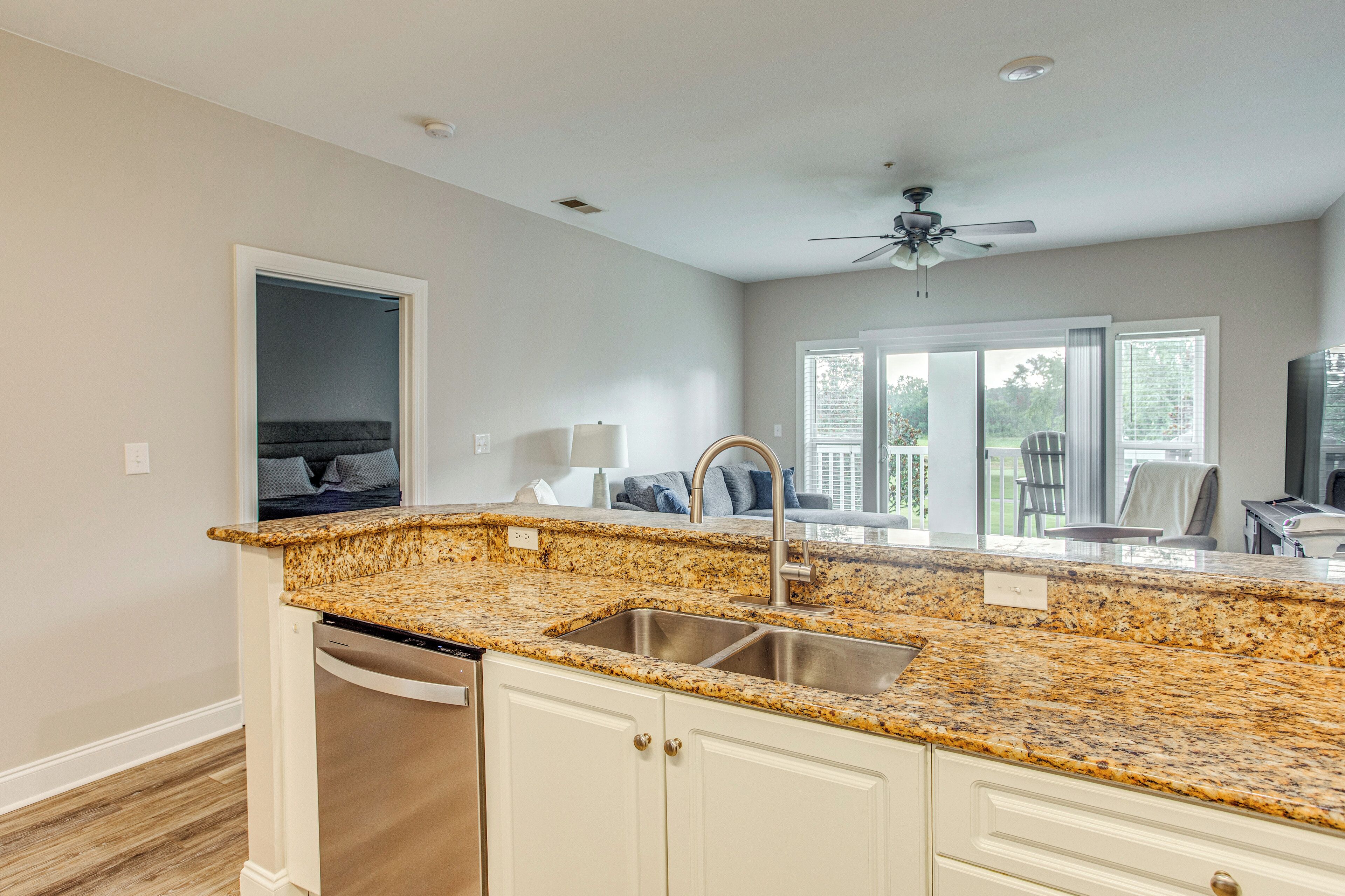 A kitchen with granite countertops, a stainless steel sink, and white cabinetry.