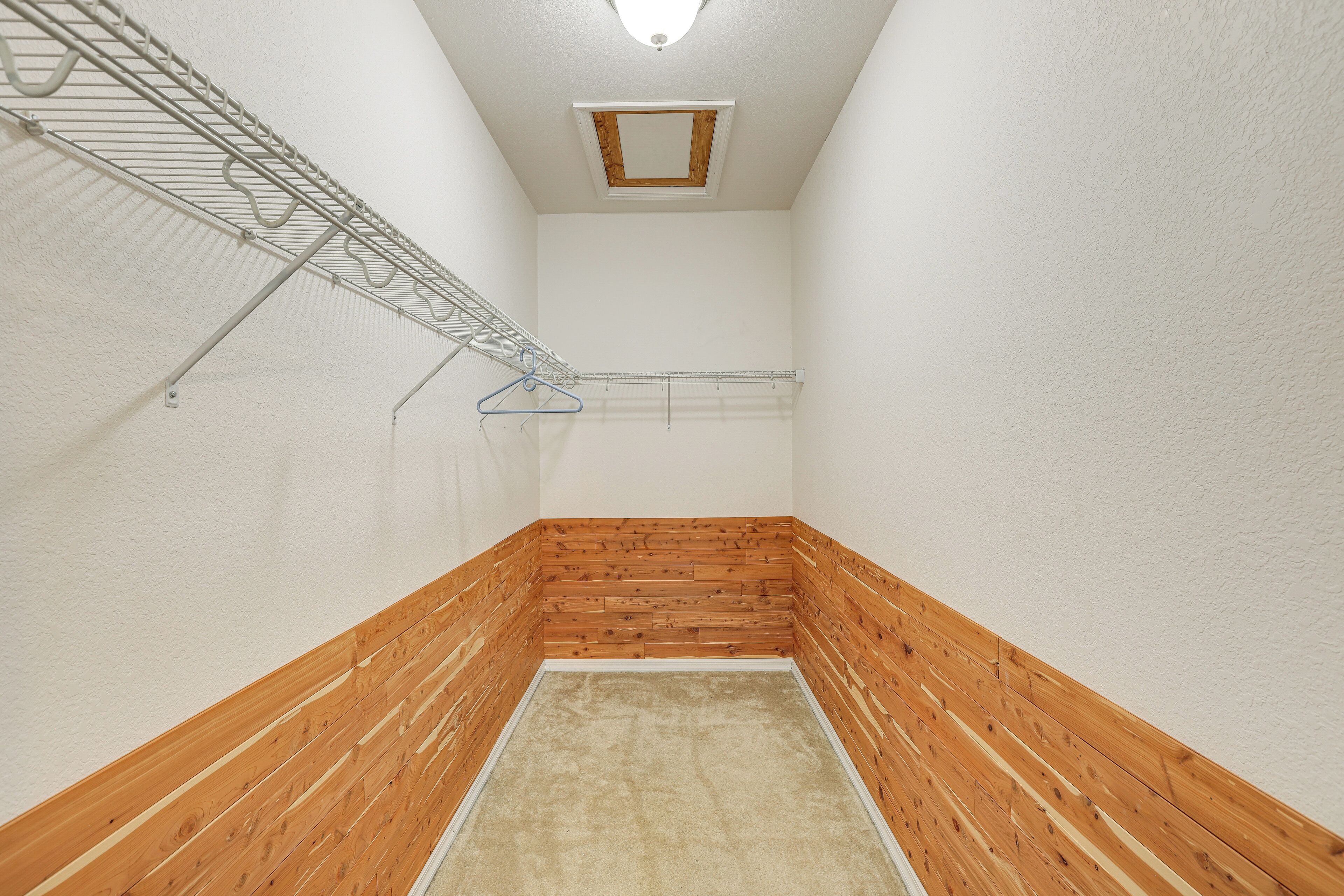 Un pasillo estrecho con paneles de madera y un estante de alambre metálico.