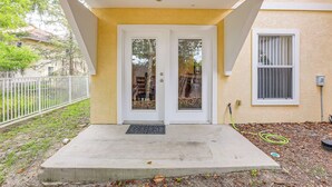 A house with a front porch, a white door with glass panels, a window with blinds, and a small garden area with mulch and a hose. - 1 Mi to UF! Gator Game Day Retreat w/ Balcony (Gainesville)
