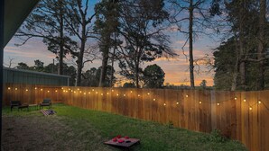 A backyard with a wooden fence, string lights, and a picnic setup. - Lake Conroe Home w/ Yard: Half-mi to Boating! (Willis)