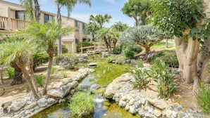 A landscaped garden with a pond, palm trees, and a wooden bridge. - Resort Perks, Ocean Access: Solana Beach Townhome! (Solana Beach)