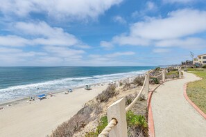 A beach with a concrete walkway, beach umbrellas, and a lifeguard tower. - Resort Perks, Ocean Access: Solana Beach Townhome! (Solana Beach)