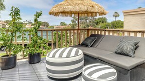 A rooftop terrace with a thatched umbrella, a grey sofa with striped ottomans, and potted plants. - Resort Perks, Ocean Access: Solana Beach Townhome! (Solana Beach)
