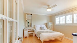 Un dormitorio con cama, escritorio, silla, cómoda y ventilador de techo.