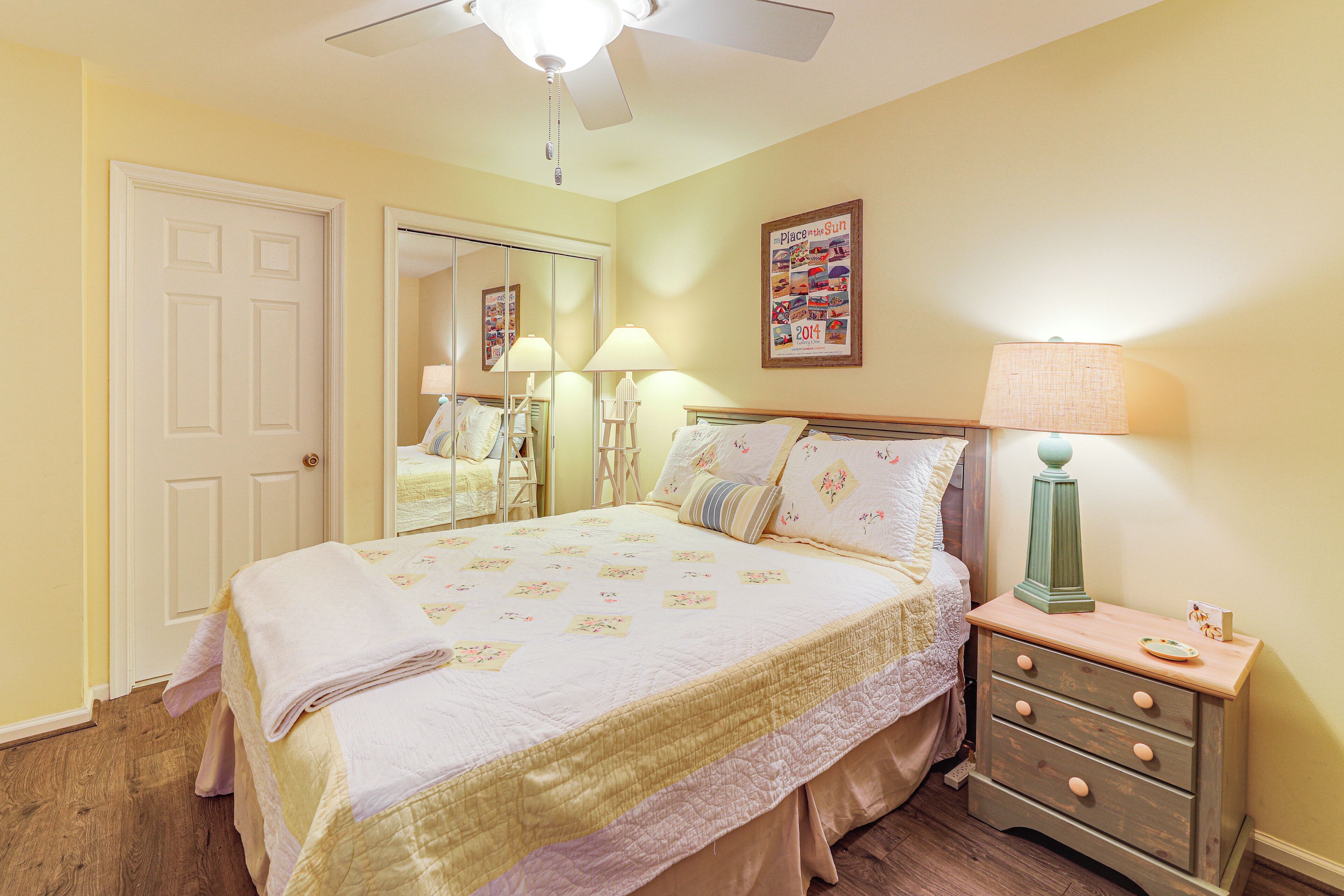 A bedroom with a bed, bedside tables, a mirror, and a ceiling fan.