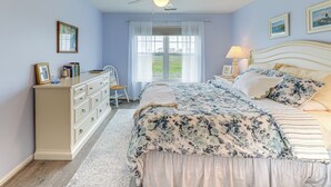 A bedroom with a bed, dresser, ceiling fan, and a window with curtains. - Swim, Fish & Explore: Marsh-front Gem in Delaware! (Ocean View)