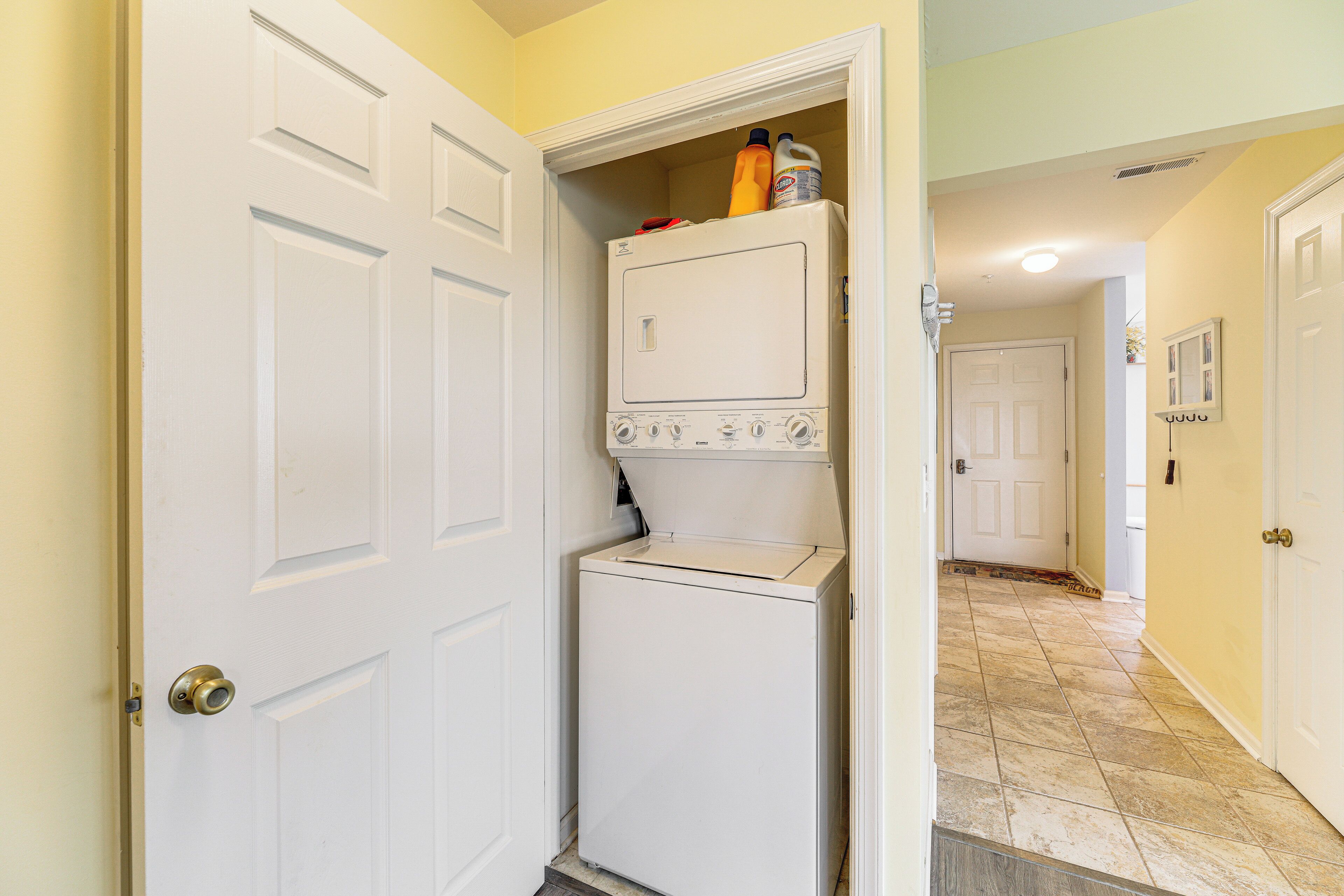 A laundry room with a washer and dryer, a door, and a hallway leading to another room.