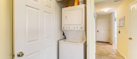 A laundry room with a washer and dryer, a door, and a hallway leading to another room.