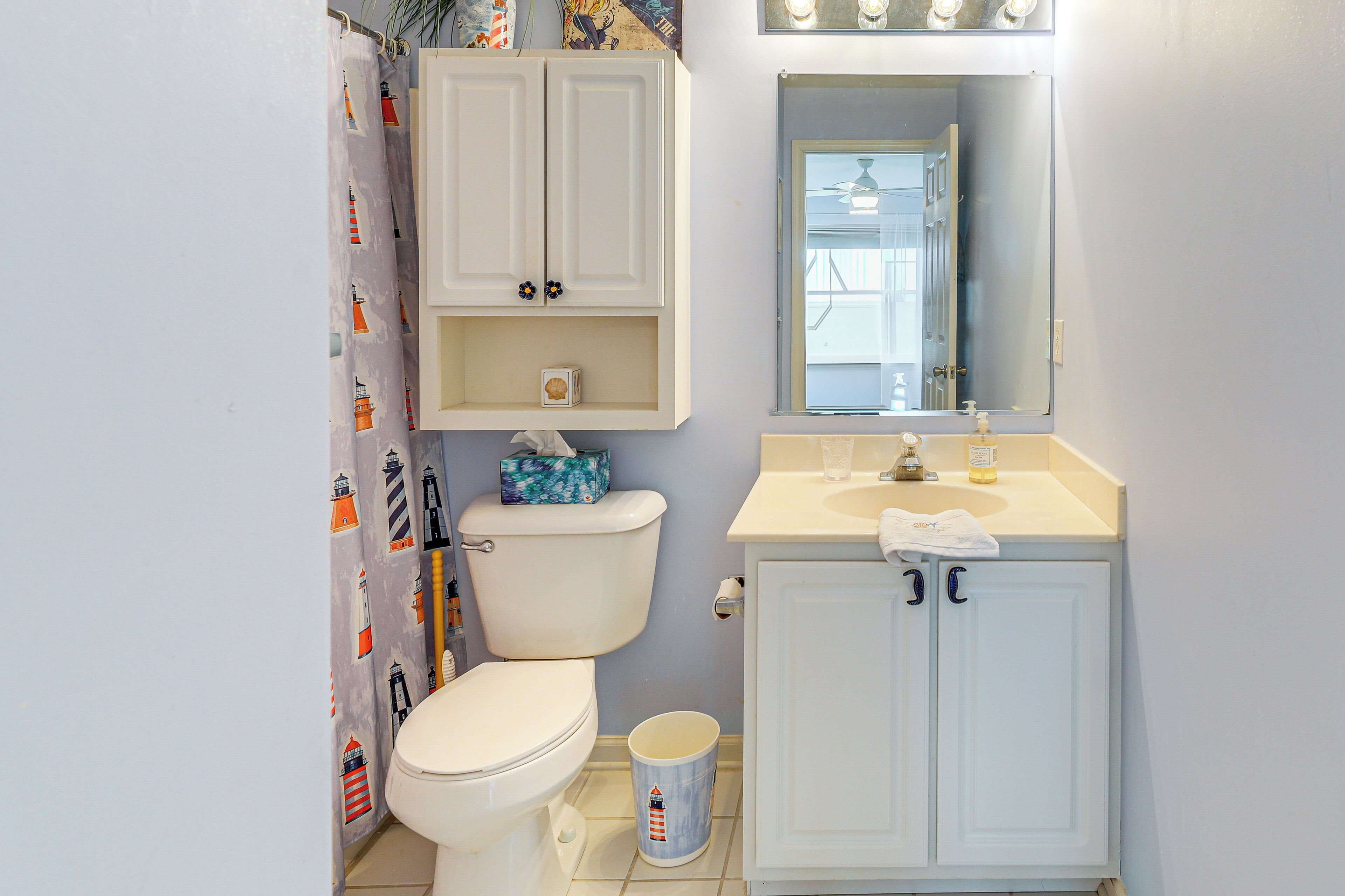 Une salle de bain comprenant des toilettes, un lavabo, un miroir et un meuble de rangement.