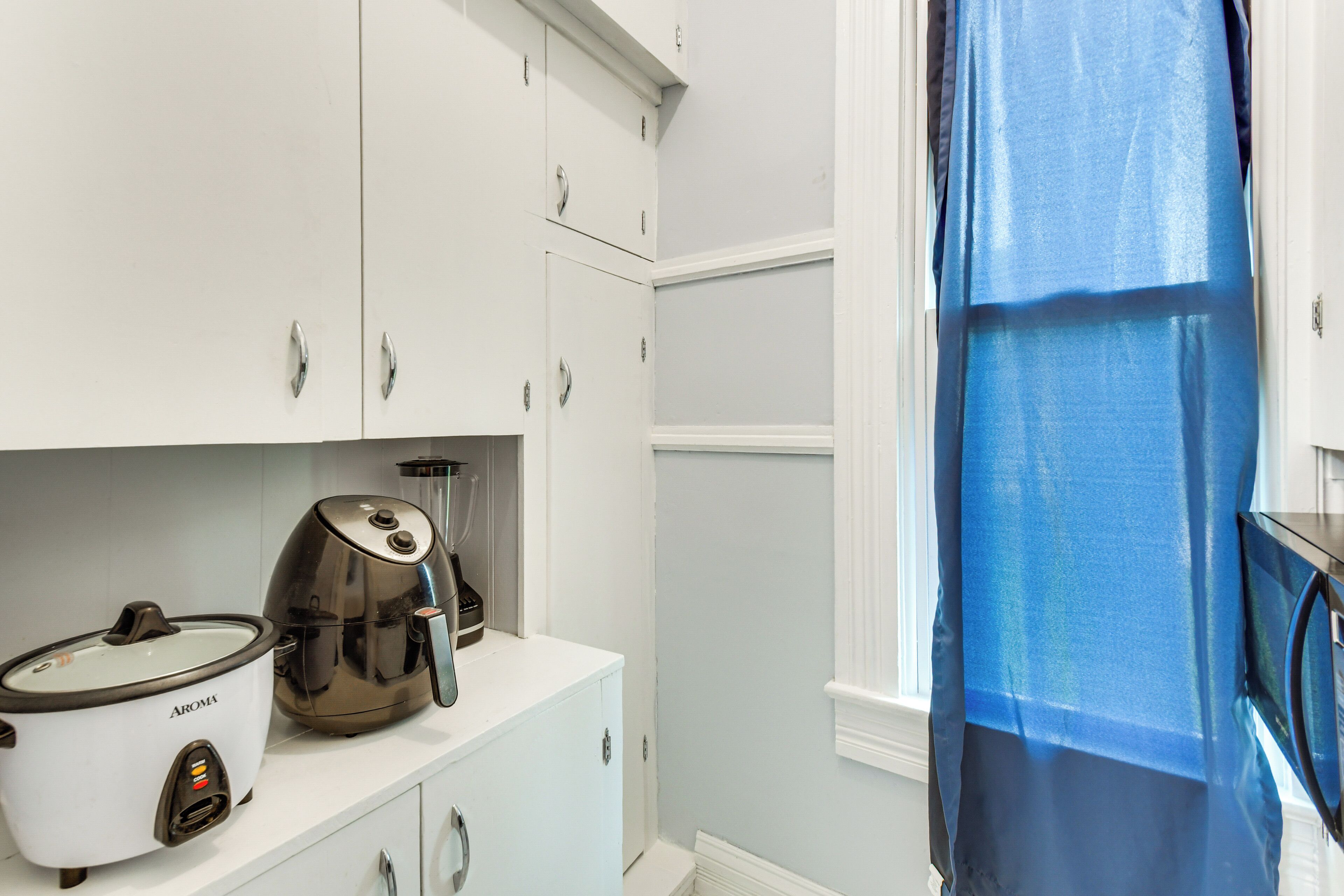 A kitchen with white cabinets, a slow cooker, and a coffee maker.