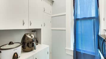 A kitchen with white cabinets, a slow cooker, and a coffee maker.