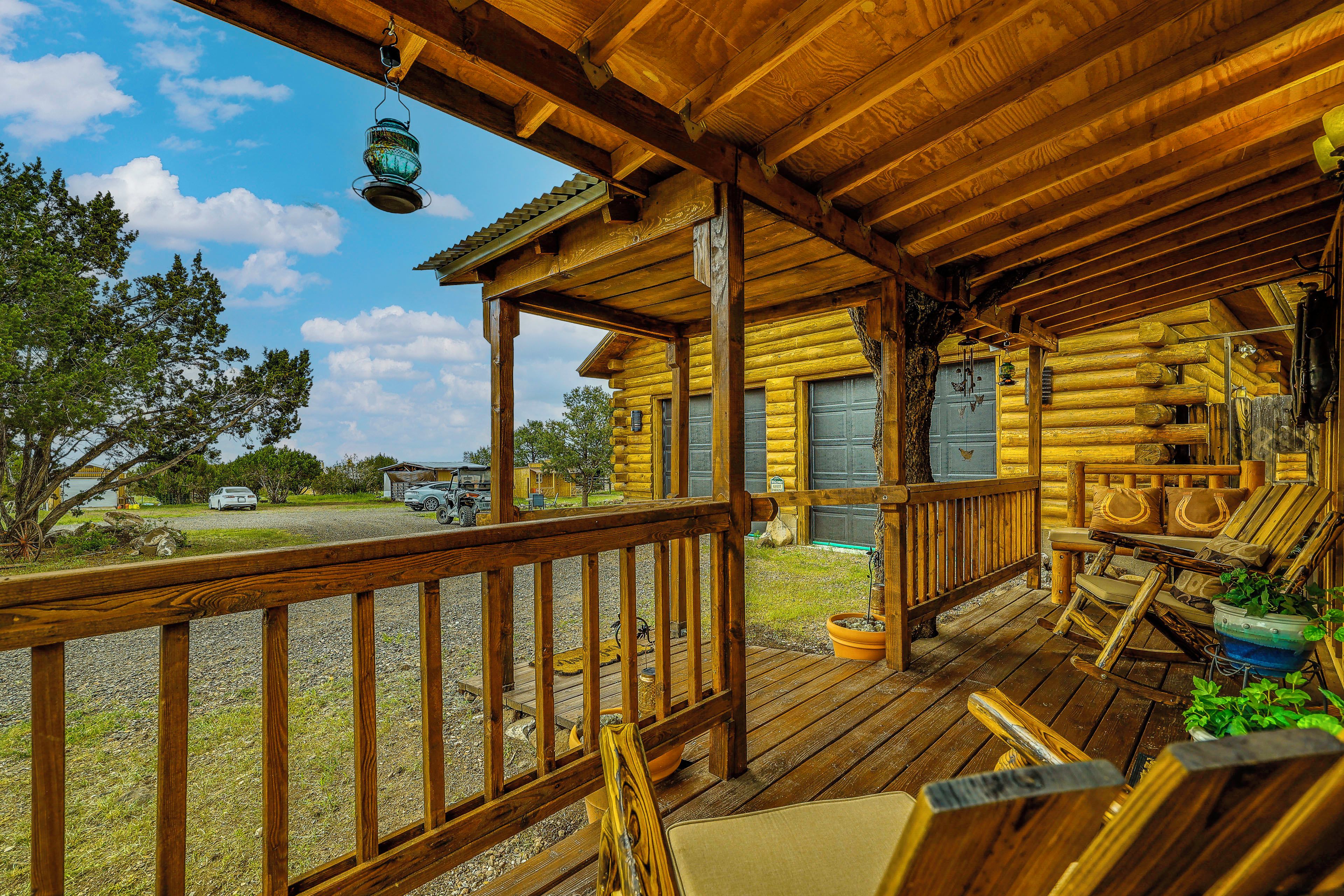 A wooden cabin with a porch, outdoor seating, and a view of the surrounding landscape.