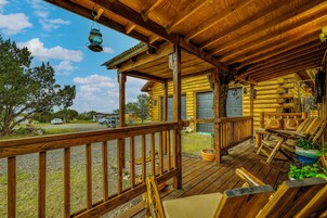 Una cabaña de madera con porche, mobiliario exterior y vistas del paisaje circundante.