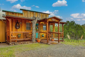 Une cabane en bois avec un porche, une pancarte de bienvenue et une vue sur la forêt environnante.