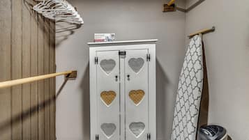 A bathroom with a white cabinet featuring heart-shaped cutouts, a shower curtain with a geometric pattern, and a wooden floor.