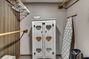 Une salle de bain avec un meuble blanc orné de découpes en forme de cœur, un rideau de douche à motifs géométriques et un plancher en bois.