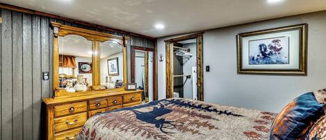A bedroom with a large bed, a dresser, a mirror, and a framed picture on the wall.