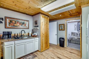 Una cocina con armarios de madera, una cafetera y un cuadro en la pared.