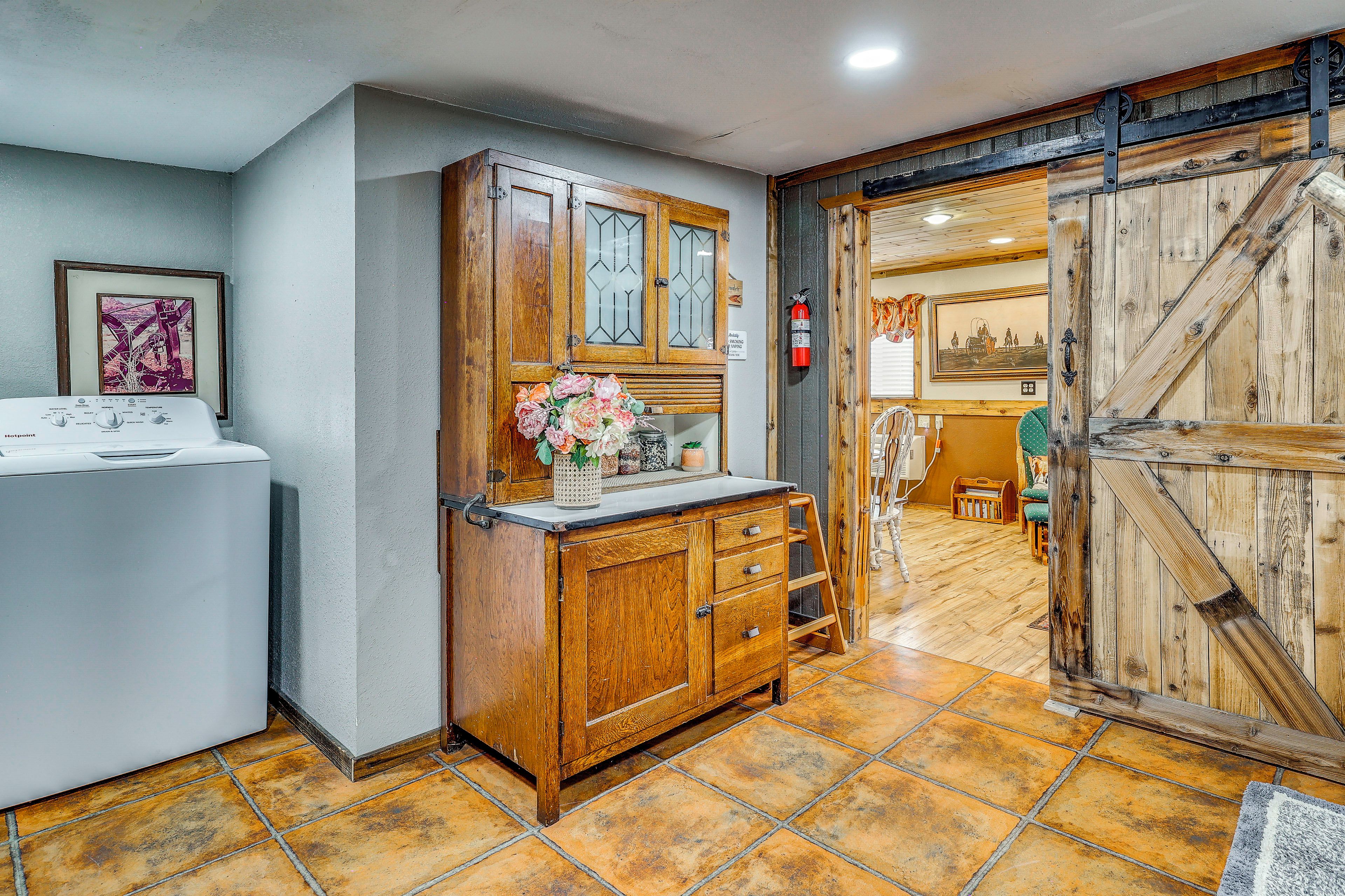 A room with a wooden cabinet, a washing machine, and a tiled floor.