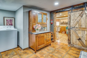 Una habitación con un armario de madera, una lavadora y piso de baldosas.