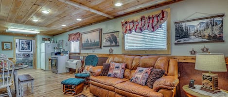 A cozy living room with a leather sofa, a patterned rug, and a dining area with a table and chairs.