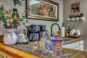 A kitchen counter with a coffee maker, a framed picture, and a basket of snacks. - Quiet Eagar Retreat Near Lakes, Hiking & Hunting! (Eagar)