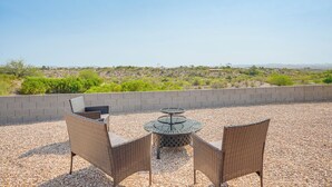 An outdoor patio with wicker furniture and a round table, overlooking a desert landscape. - Golfer's Oasis! Mtn-view Arizona Desert Escape (Wickenburg)