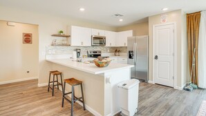 A modern kitchen with white cabinetry, stainless steel appliances, and a central island with stools. - Golfer's Oasis! Mtn-view Arizona Desert Escape (Wickenburg)
