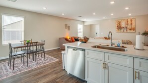 A modern kitchen with a central island, white cabinetry, and a dining area with a patterned rug. - Golfer's Oasis! Mtn-view Arizona Desert Escape (Wickenburg)
