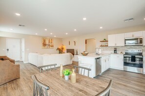 A modern kitchen with white cabinets, a stainless steel oven, and a microwave.